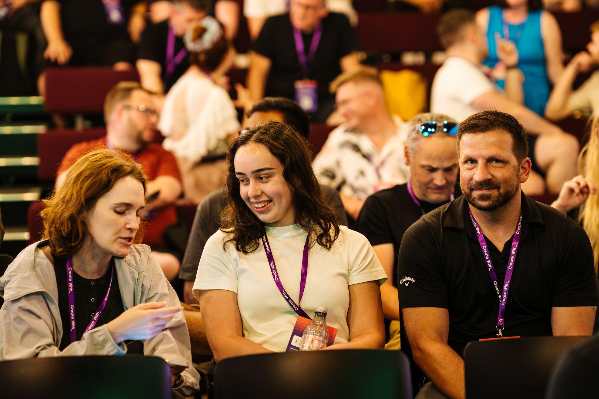 Attendees in the audience talking and laughing between sessions