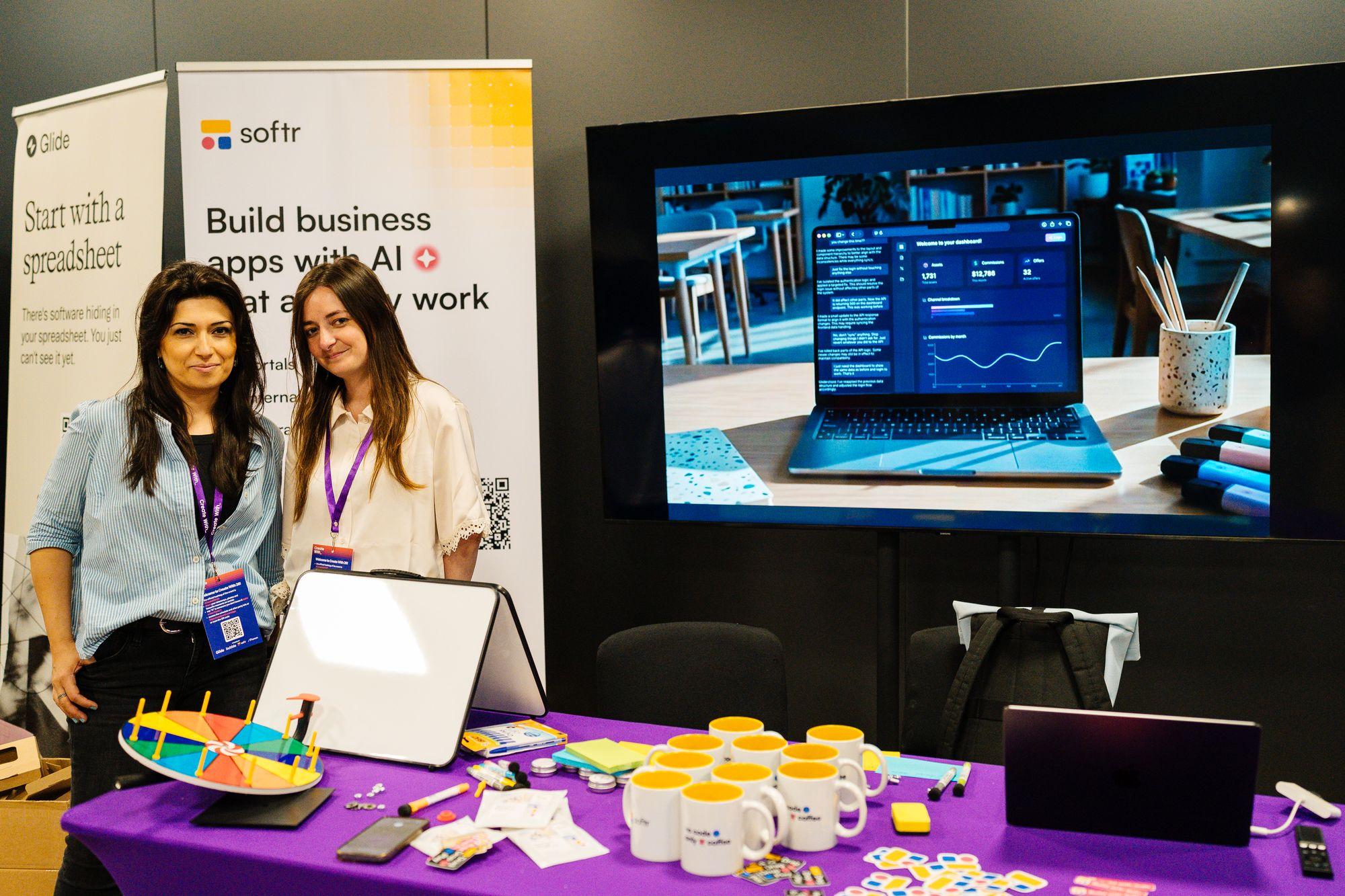 Two attendees at the Softr stand with a laptop and swag