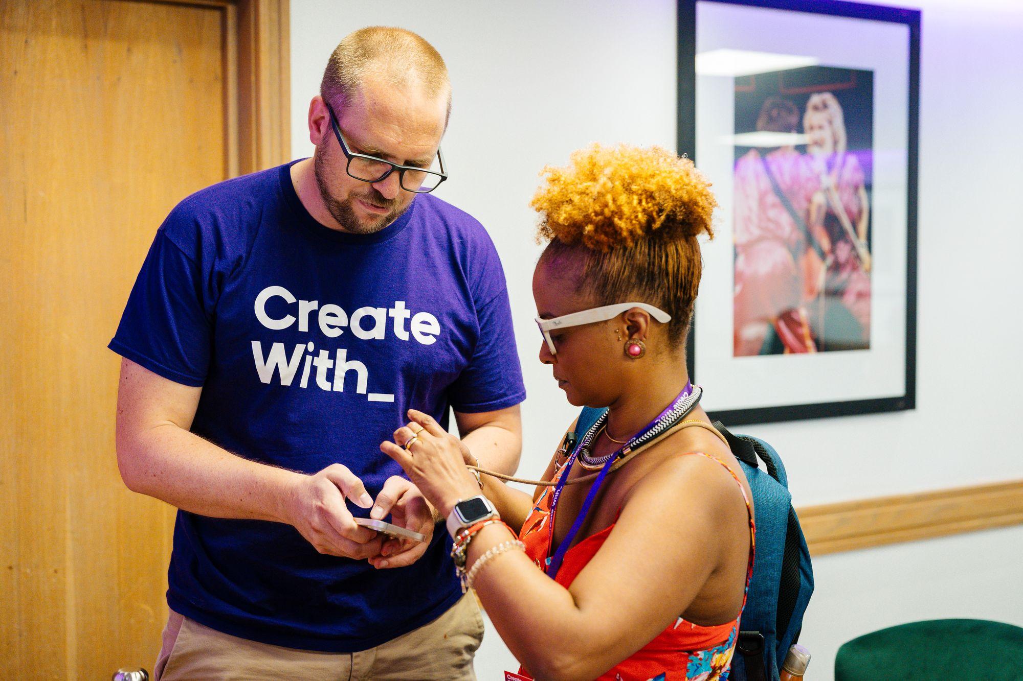 A Create With team member helping an attendee with her phone