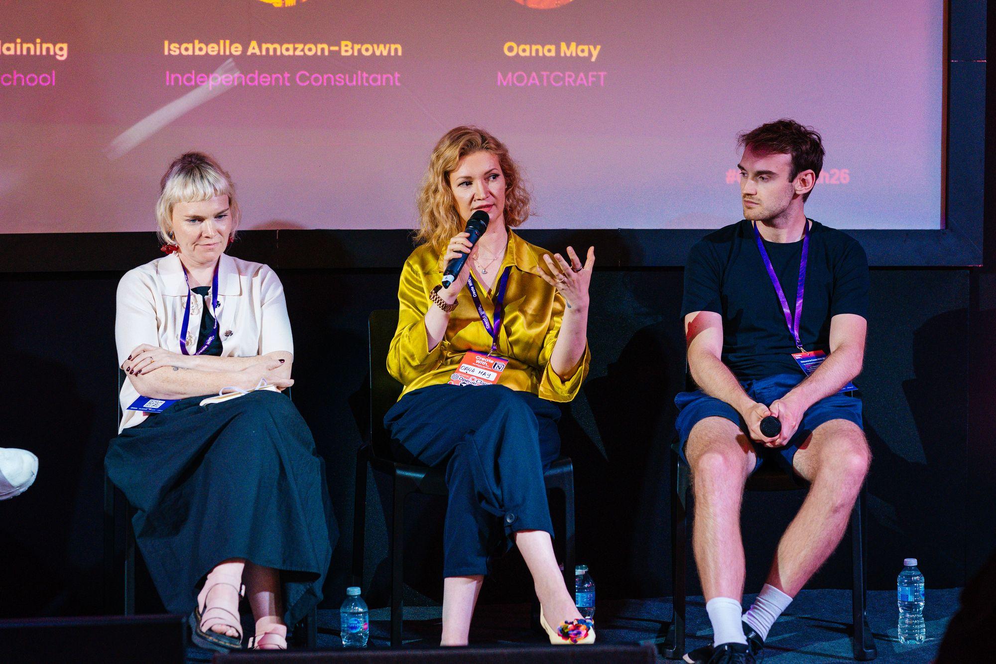 Three panellists seated on stage, one speaking