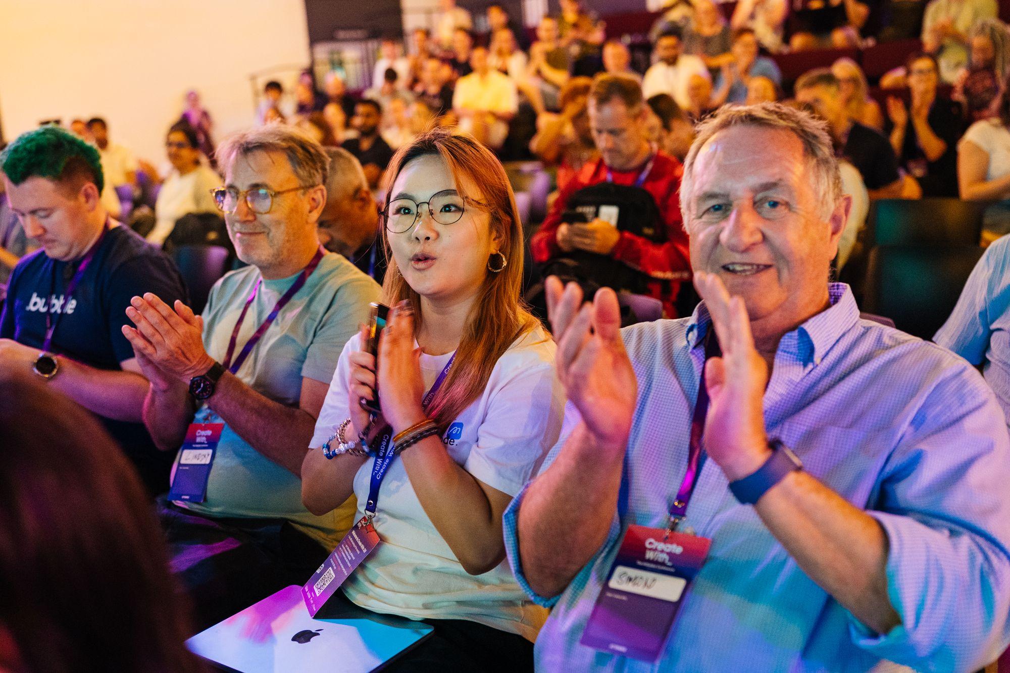 The audience applauding, faces lit by the stage